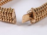 a close up of a gold bracelet on a white surface