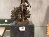 une statue en bronze d'une femme tenant un oiseau sur un piédestal