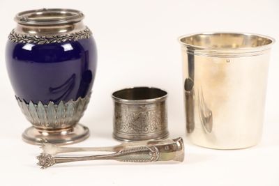un vase bleu, une tasse en argent et une cuillère posés sur une table