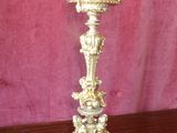 a gold candle holder on a wooden table with a pink background