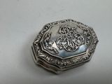 an antique silver box with a floral design on the lid