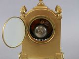 a gold clock with a mirror on top of it