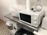 a microwave sitting on top of a table next to a trash bag