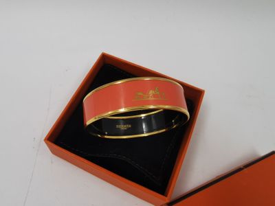 un bracelet orange et noir dans une boîte posée sur une surface blanche