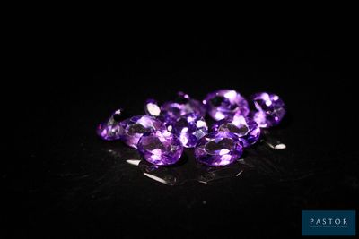 un gros plan sur un bouquet de pierres précieuses violettes posées sur une surface noire