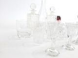 des bouteilles et des verres sont alignés sur une table à fond blanc