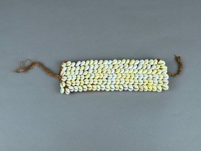 un gros plan d'un bracelet composé de perles blanches et jaunes posé sur une surface grise