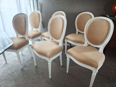 quatre chaises blanches aux assises rembourrées beiges dans une pièce