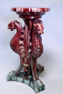 un vase rouge orné d'un dragon, posé sur un socle