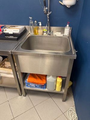 un évier en acier inoxydable dans un coin d'une salle de bains bleue