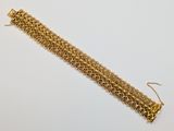 gros plan d'un bracelet en chaîne en or sur une surface blanche