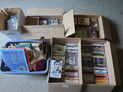 Plusieurs cartons remplis de livres sont empilés les uns sur les autres par terre