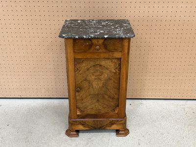 une vieille armoire en bois avec un plateau en marbre, posée à même le sol
