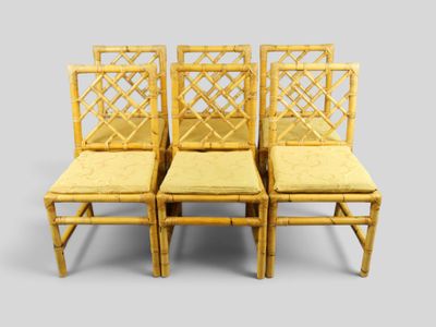 quatre chaises en bambou avec des coussins jaunes sur fond gris