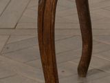 an old wooden chair with a brown upholstered seat on a tile floor