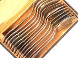 six fourchettes dans un étui posé sur une surface blanche