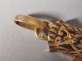 a close up of a gold pendant on a white surface
