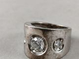 a close up of a silver ring with two diamonds on it