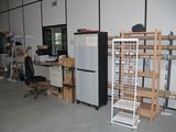 a room with a refrigerator, shelves, and a chair in it