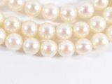 a close up of three strands of white pearls on a white surface