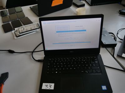 un ordinateur portable posé sur un bureau, à côté d'autres ordinateurs portables