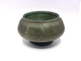 a close up of a small green bowl on a white surface
