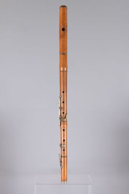 a wooden flute on a clear stand against a gray background
