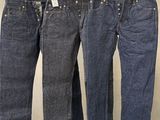 trois paires de jeans suspendues à un portant dans un magasin