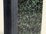 a black book with green speckles sitting on a white surface