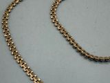 a gold chain necklace with a clasp on a gray surface