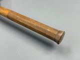 une batte de baseball en bois posée sur une table à la surface grise
