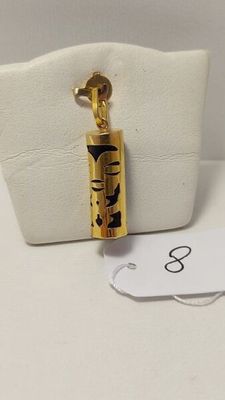 un petit sac blanc sur lequel est accroché un collier en or