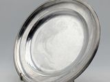 assiette en argent sur un support, sur fond gris avec un fond blanc