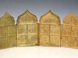 trois portes métalliques dorées ornées de sculptures sur un fond blanc