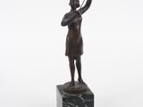 statue d'une femme tenant une raquette de tennis, posée sur un socle en marbre