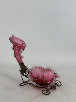 un vase en verre rose posé sur un socle en métal