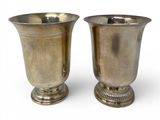 two silver vases sitting next to each other on a white surface