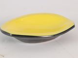 un bol jaune et noir posé sur une surface blanche