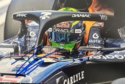 photo dédicacée d'une voiture de course avec un casque sur le capot
