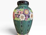 un vase vert sur lequel sont peintes des fleurs, sur un fond blanc