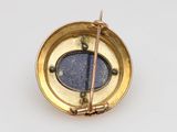 a gold compass with a blue stone in the middle