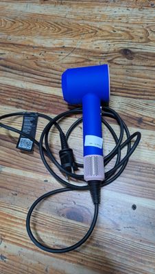 a blue blow dryer sitting on top of a wooden floor