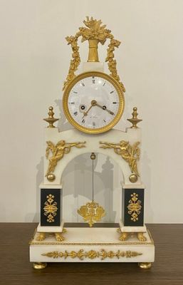 a white and gold clock sitting on a wooden table