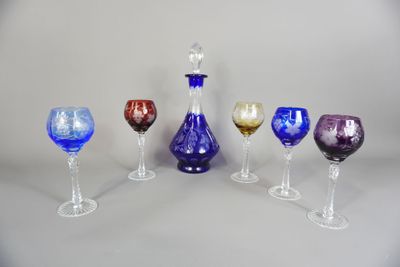 plusieurs verres à vin de différentes couleurs et une carafe posés sur une table