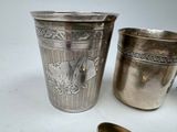 two silver cups and a spoon on a table