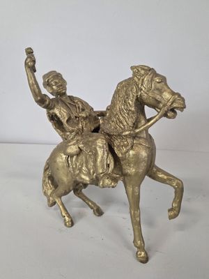 brass statue of a man riding a horse with a woman on the back