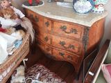 une petite poupée assise sur une chaise à côté d'une commode