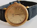 an image of a gold wrist watch on a black leather strap