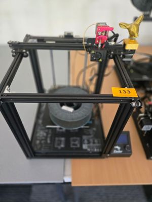 une imprimante 3D posée sur un bureau, à côté d'une imprimante