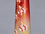 un vase rouge orné de fleurs, posé sur une table